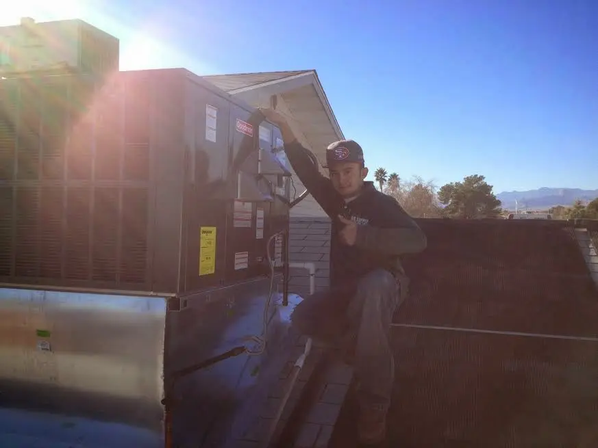 HVAC technician performing AC Tune-Up on a rooftop unit in Sandy